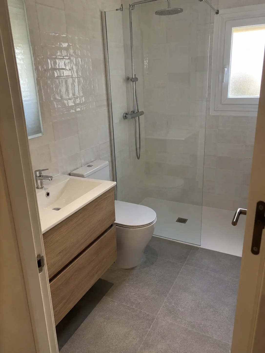 Baño reformado con mueble de madera y ducha amplia